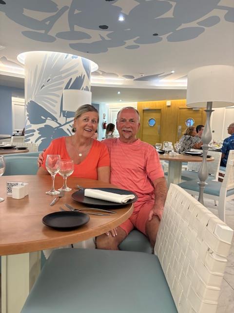 Bob Berezowski and his wife smiling together at a restaurant during their travels, reflecting the couple's shared love of travel and the new adventures ahead in retirement