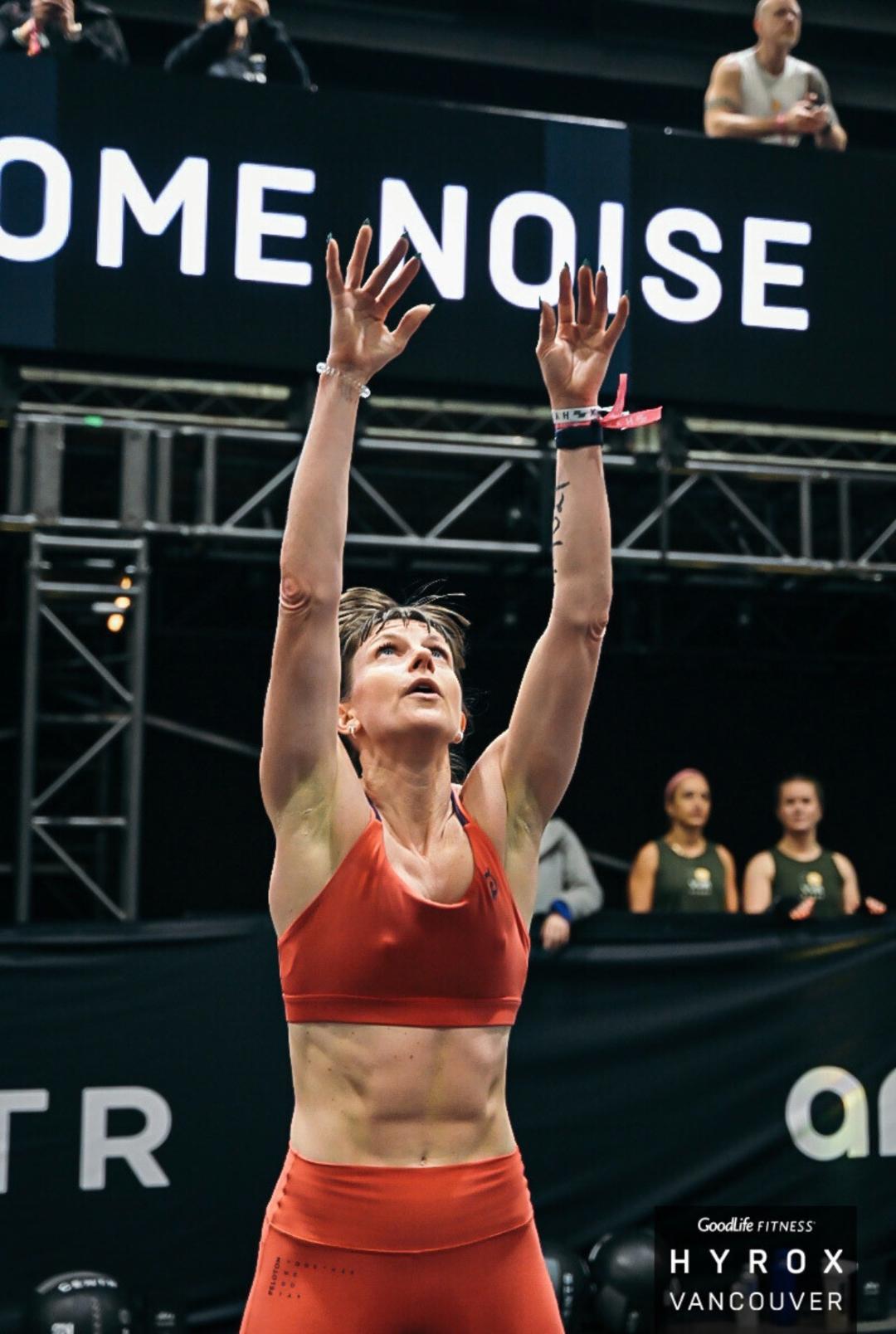 Athlete in red sports attire with arms raised celebrating at an indoor fitness competition in Vancouver. Athlete in red sports attire with arms raised celebrating at an indoor fitness competition in Vancouver.