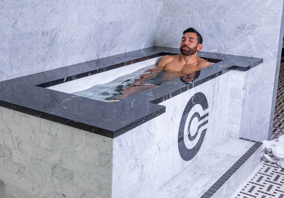 Young man sitting in the cold plunge in the Cambridge Club's locker room