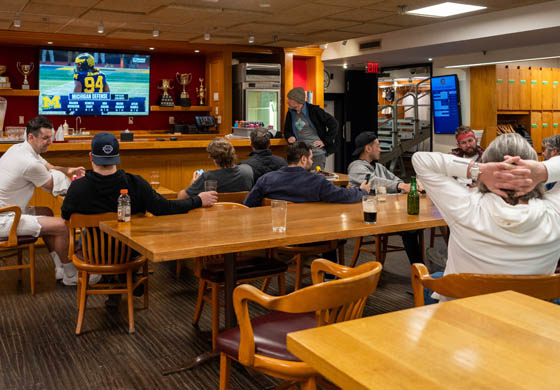 Group of men sitting in the sports lounge in the Cambridge Club's locker room, watching a soccer game on the tv