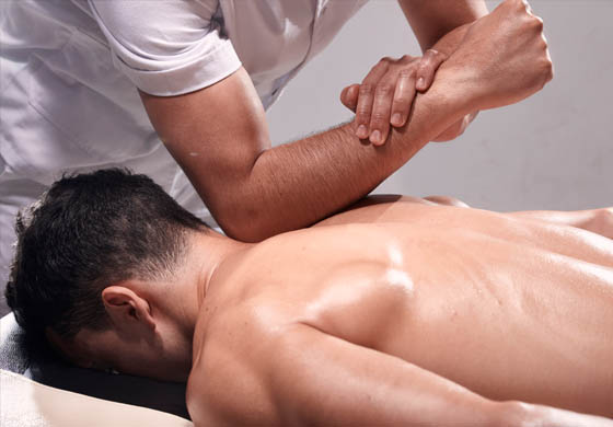 Masseur using his elbow to work on a knot on the back of a male massage client