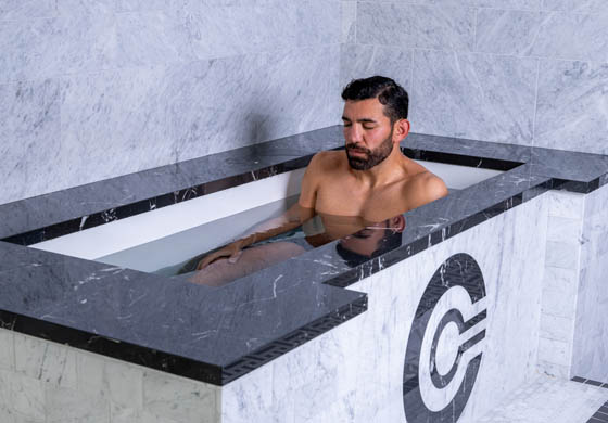 Young, fit man sitting in the cold plunge in the Cambridge Club's wet area