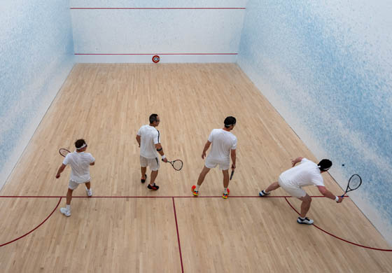 Four men playing squash on the doubles squash court at the Cambridge Club