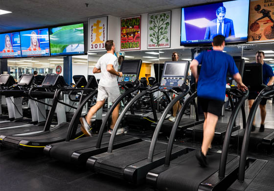 Two men running on treadmills together in the Cambridge Club gym