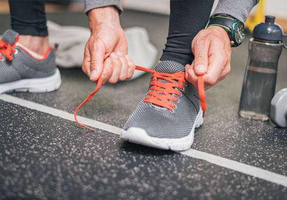 Close-up of fit man tying his running shoes on the gym floor