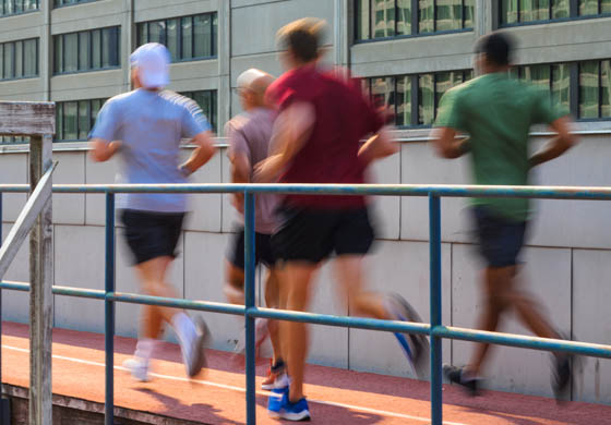 Four fit men running on the outdoor rooftop running track at the Cambridge Club
