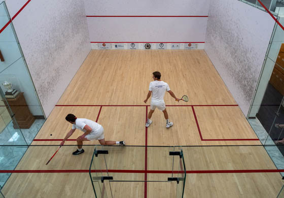 Overhead view of two young men playing squash on the singles squash court at the Cambridge Club