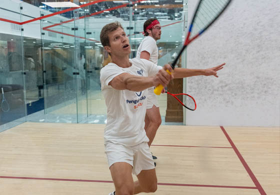 Two young guys playing squash on a singles court at the Cambridge Club