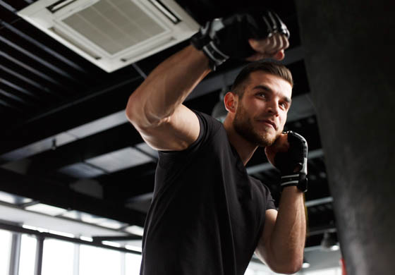 Young man, smirking as he punches towards a punching bag