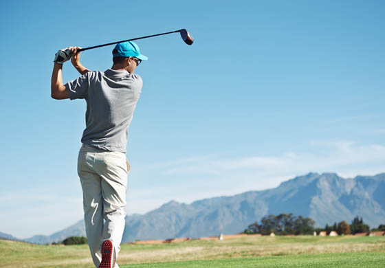 Young man completing a drive on the golf course