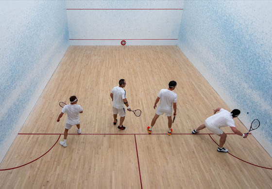 Four men play a squash game on the Cambridge Club doubles squash court